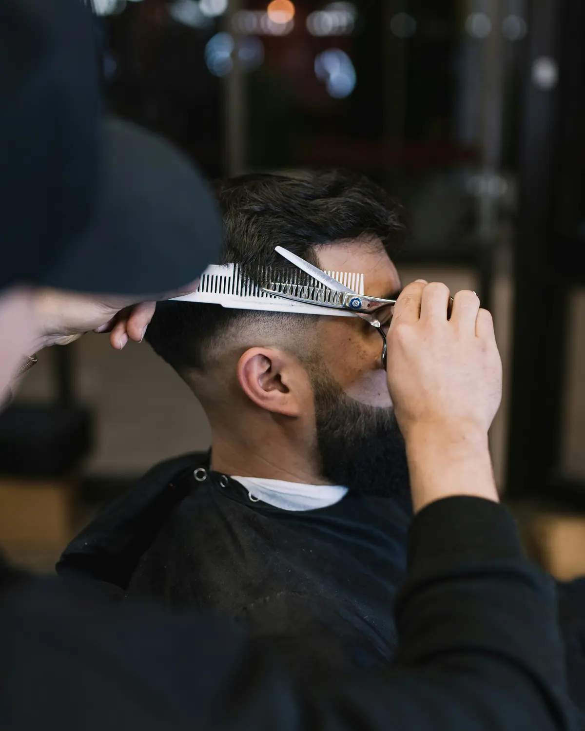 Barber blending a fade with scissors